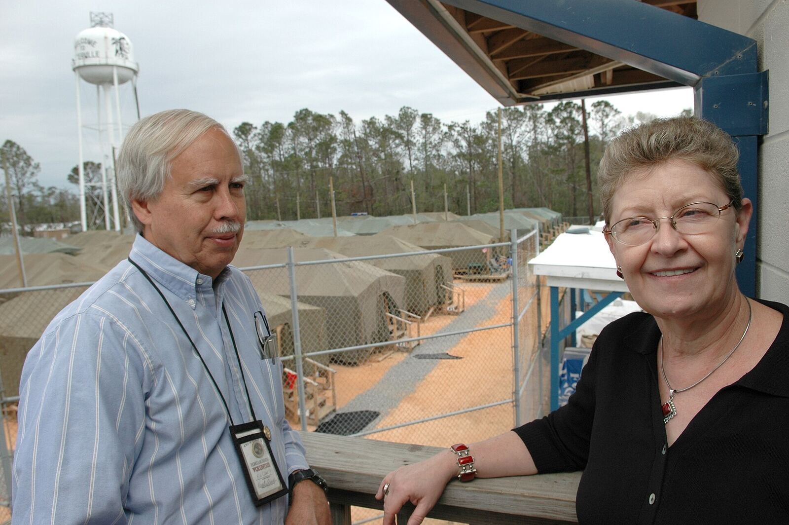Couple and Shelter | The Life After Tragedy A couple stands on a porch overlooking temporary shelters, documenting loss recovery after catastrophe.