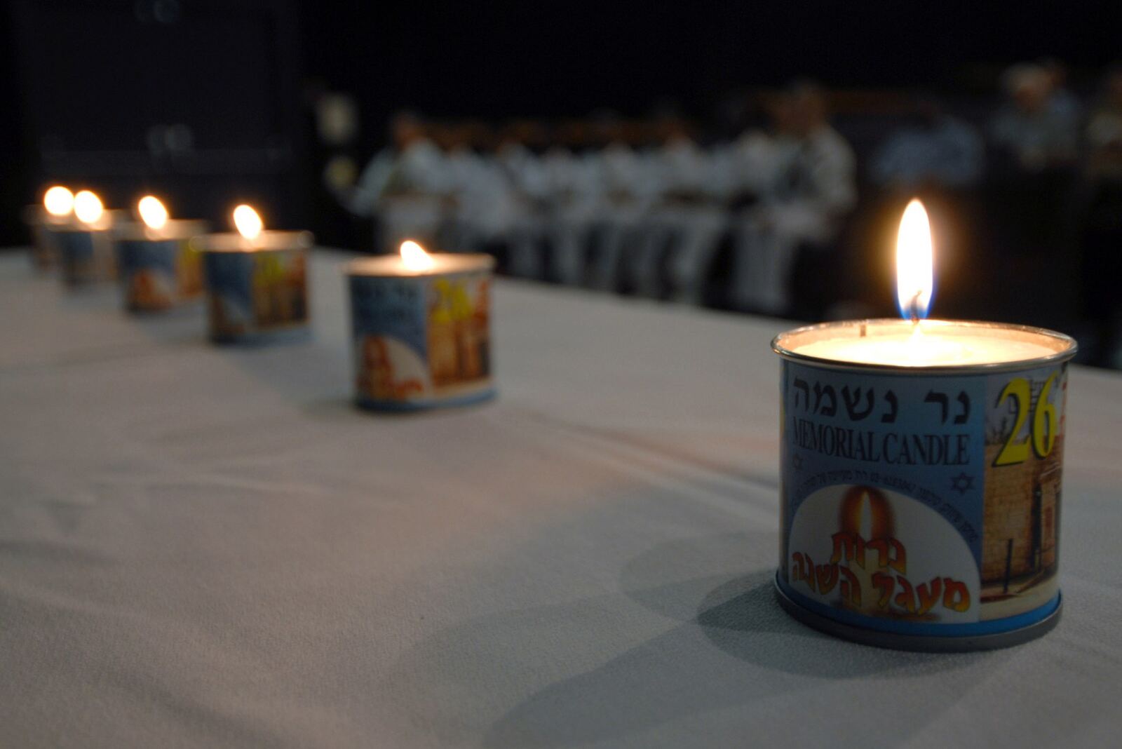 Six memorial candles burn during a Holocaust Remembrance Day ceremony, honoring memory and loss.