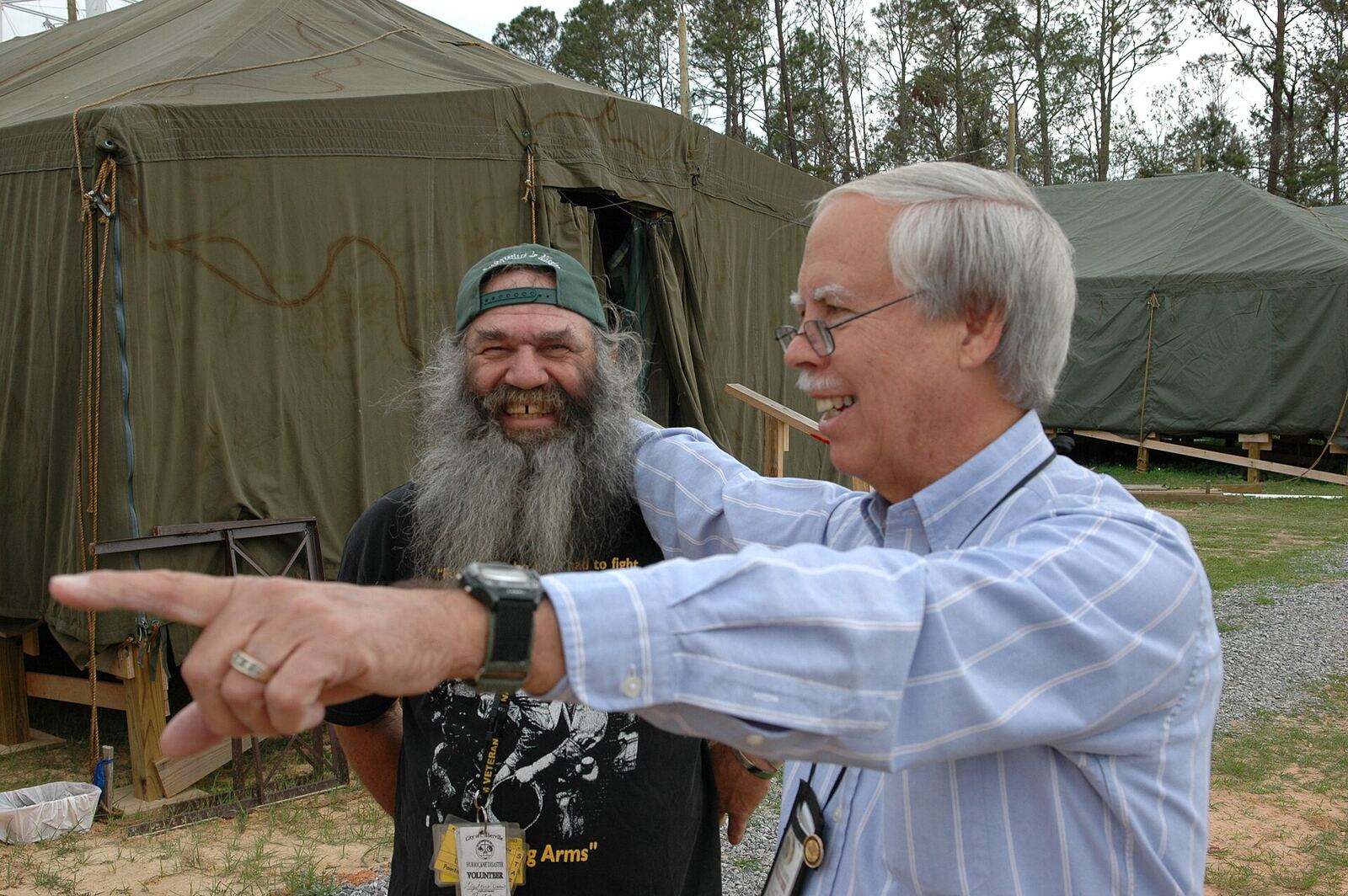 Phil Robertson | The Life After Tragedy Phil Robertson and another man are outdoors near tents, showing a moment of connection and resilience.