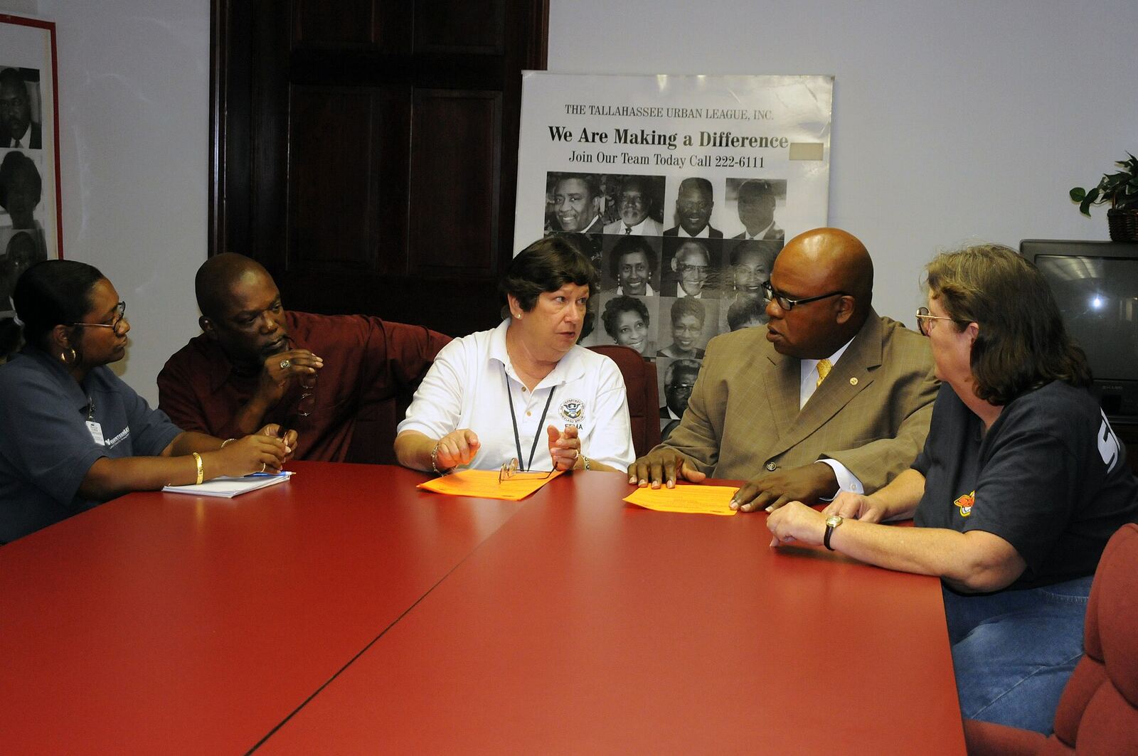 Tallahassee Urban League | The Life After Tragedy A group discusses issues around a conference table with The Tallahassee Urban League banner visible, supporting community.