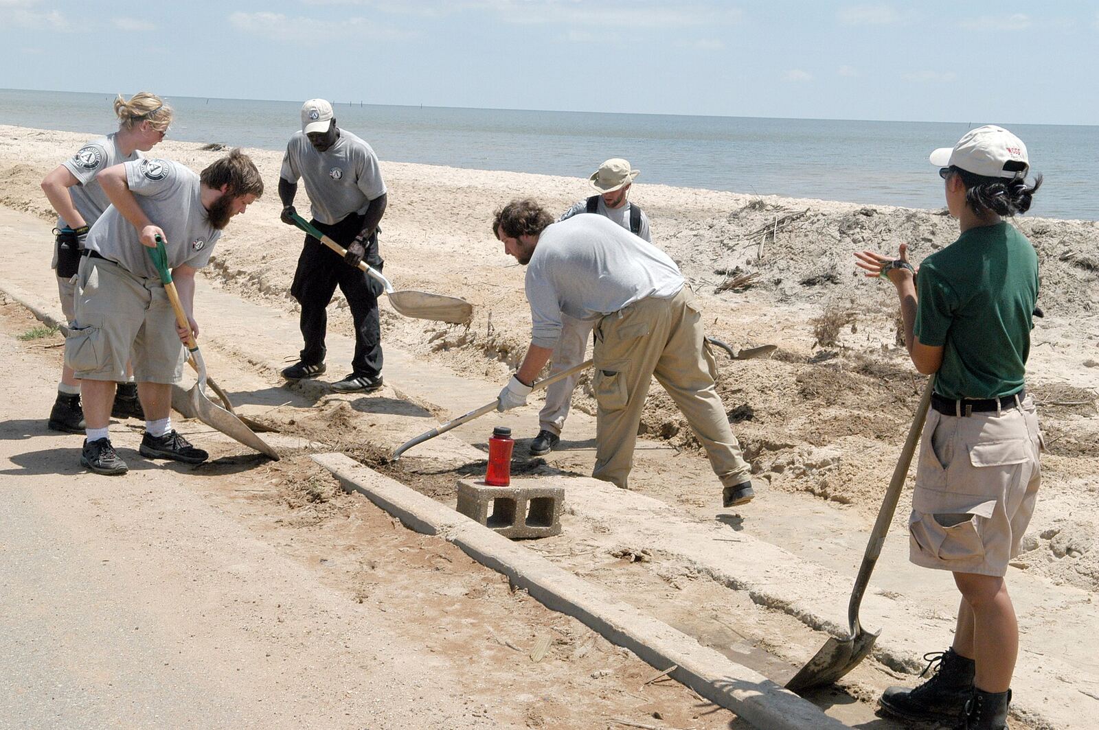 Waveland Beach Restoration | The Life After Tragedy An AmeriCorps team cleans debris from Waveland beach after a disaster, supporting grief recovery and community resilience.