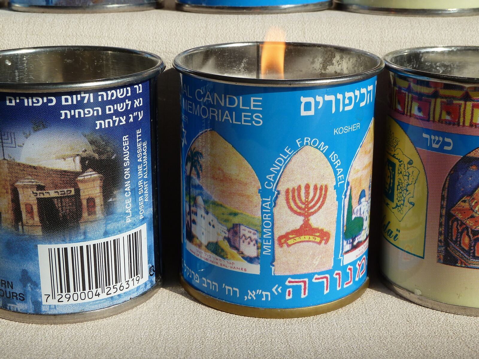 A lit yahrzeit candle reflects on a surface, representing Jewish tradition and remembrance.